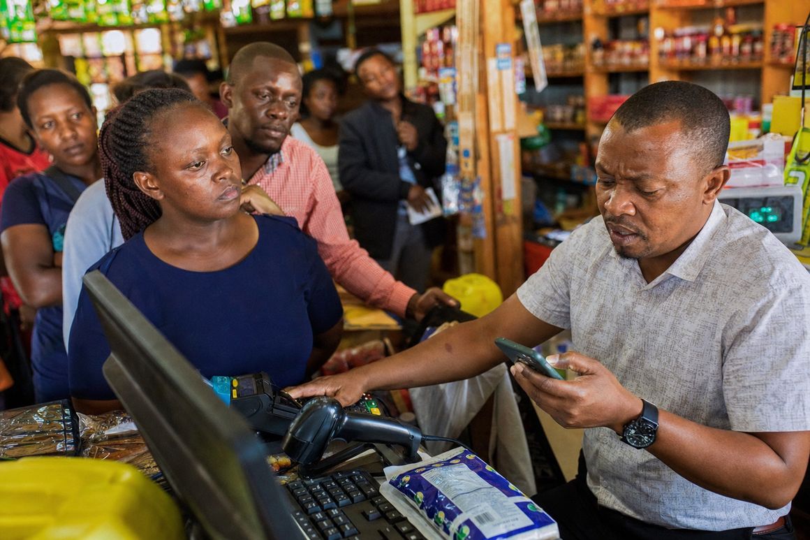 Long checkout queue at a busy Kenyan shop with a stressed cashier checking M-Pesa messages